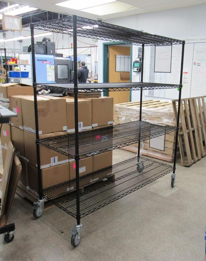Black wire shelving unit on wheels, holding boxes in a warehouse setting.