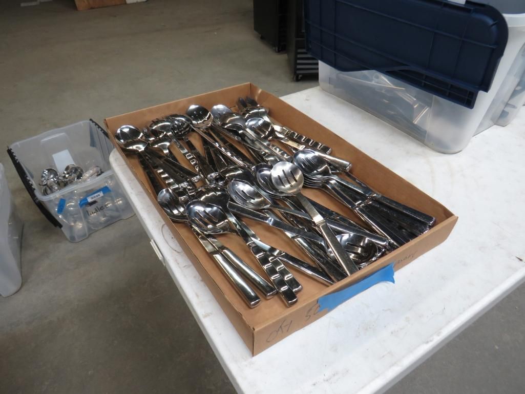 A box of shiny chrome tools on a white surface, kitchen utencils.