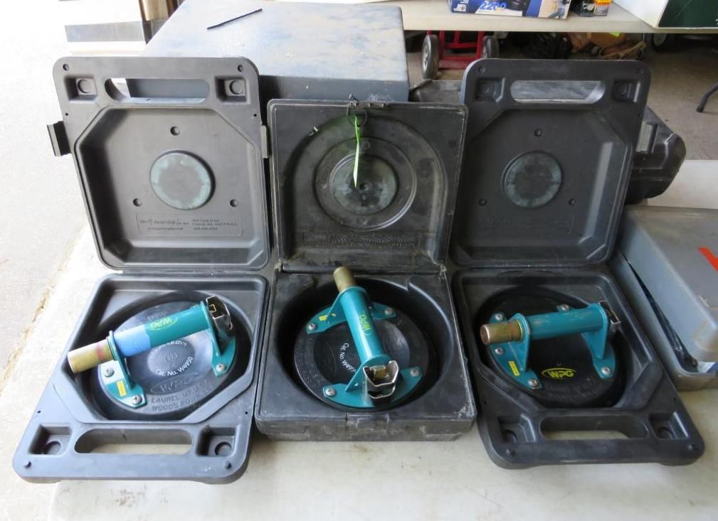 Three suction cup glass lifters in open black carrying cases on a table.