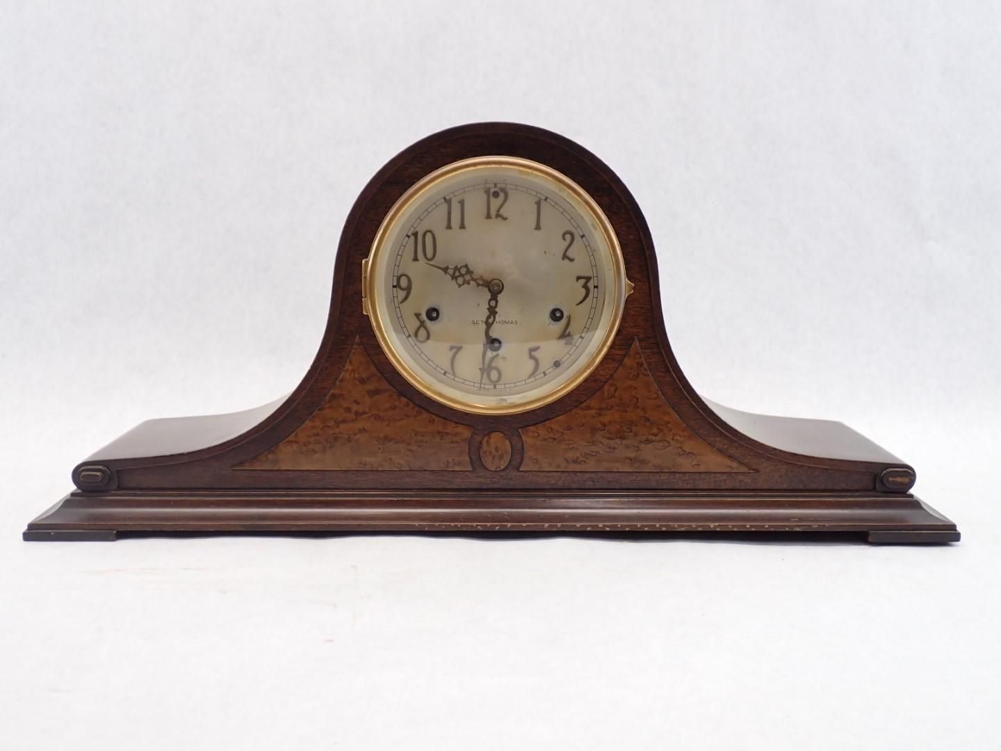 Wooden mantel clock with gold-rimmed face and Roman numerals, set on a curved base.