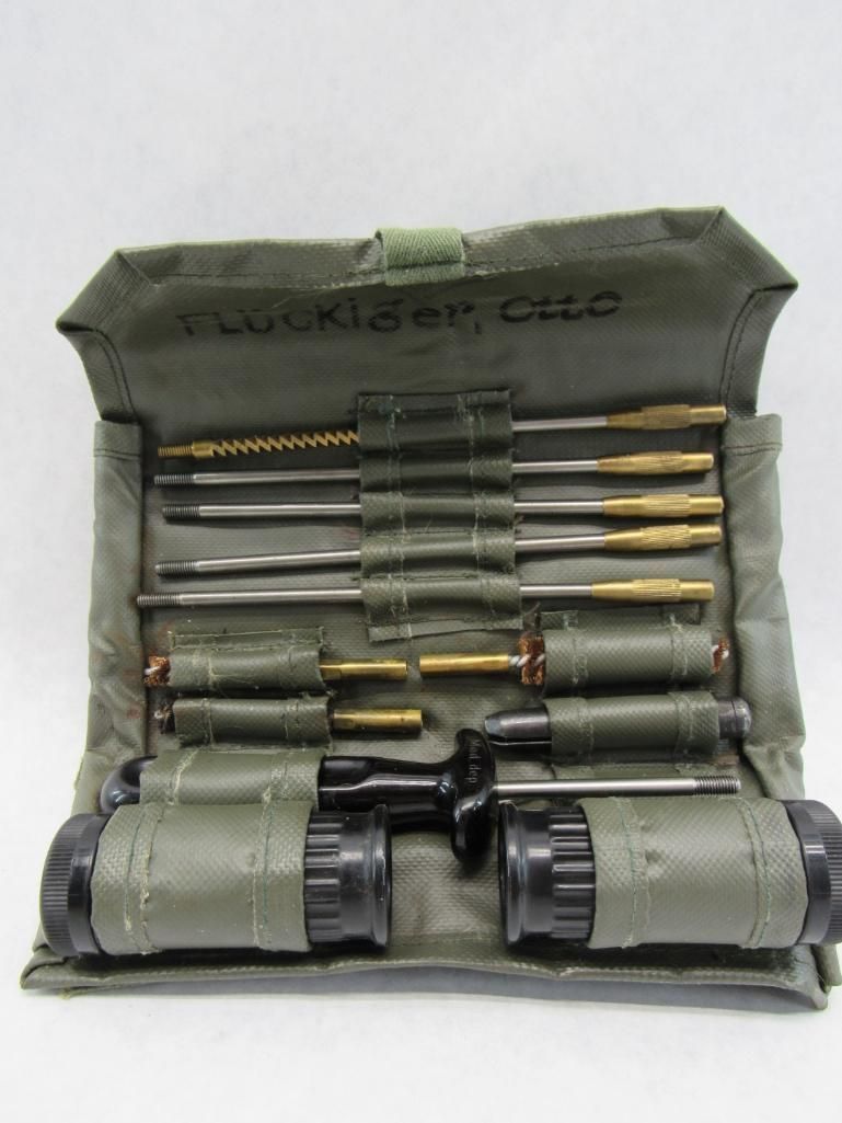 Green canvas gun cleaning kit, open, with various cleaning rods, brushes, and tools visible.