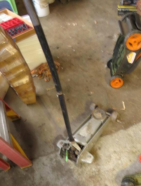 A silver floor jack with a black handle.