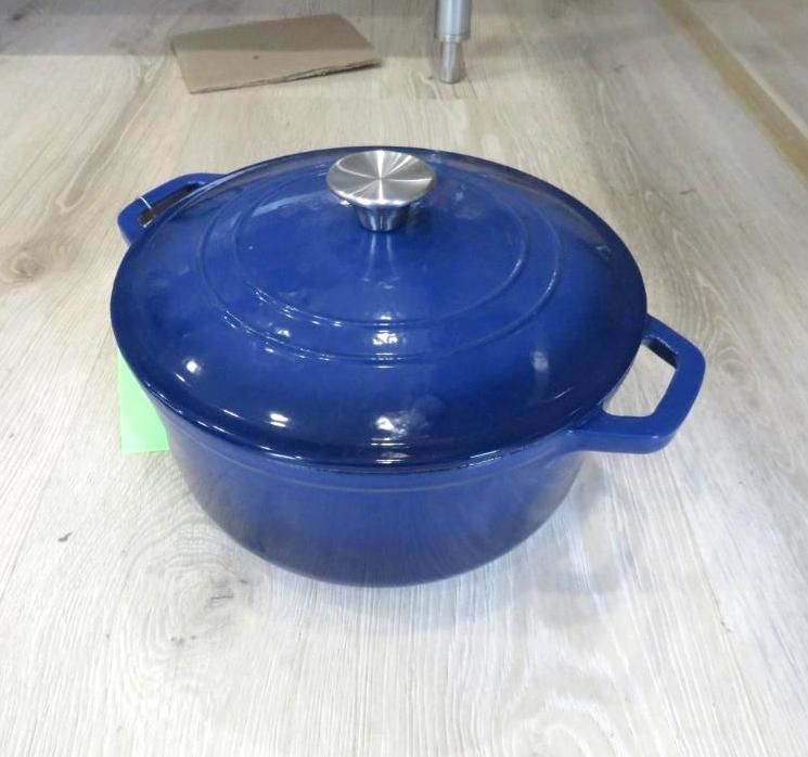 Blue cast iron Dutch oven with lid on a light wood surface.