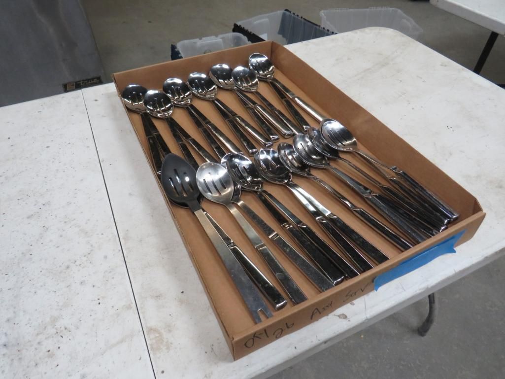 Silverware arranged in a brown cardboard box on a white table.
