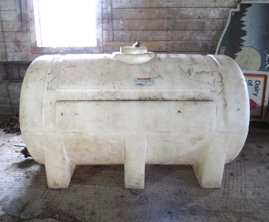 White plastic horizontal tank with supports in a wooden barn.
