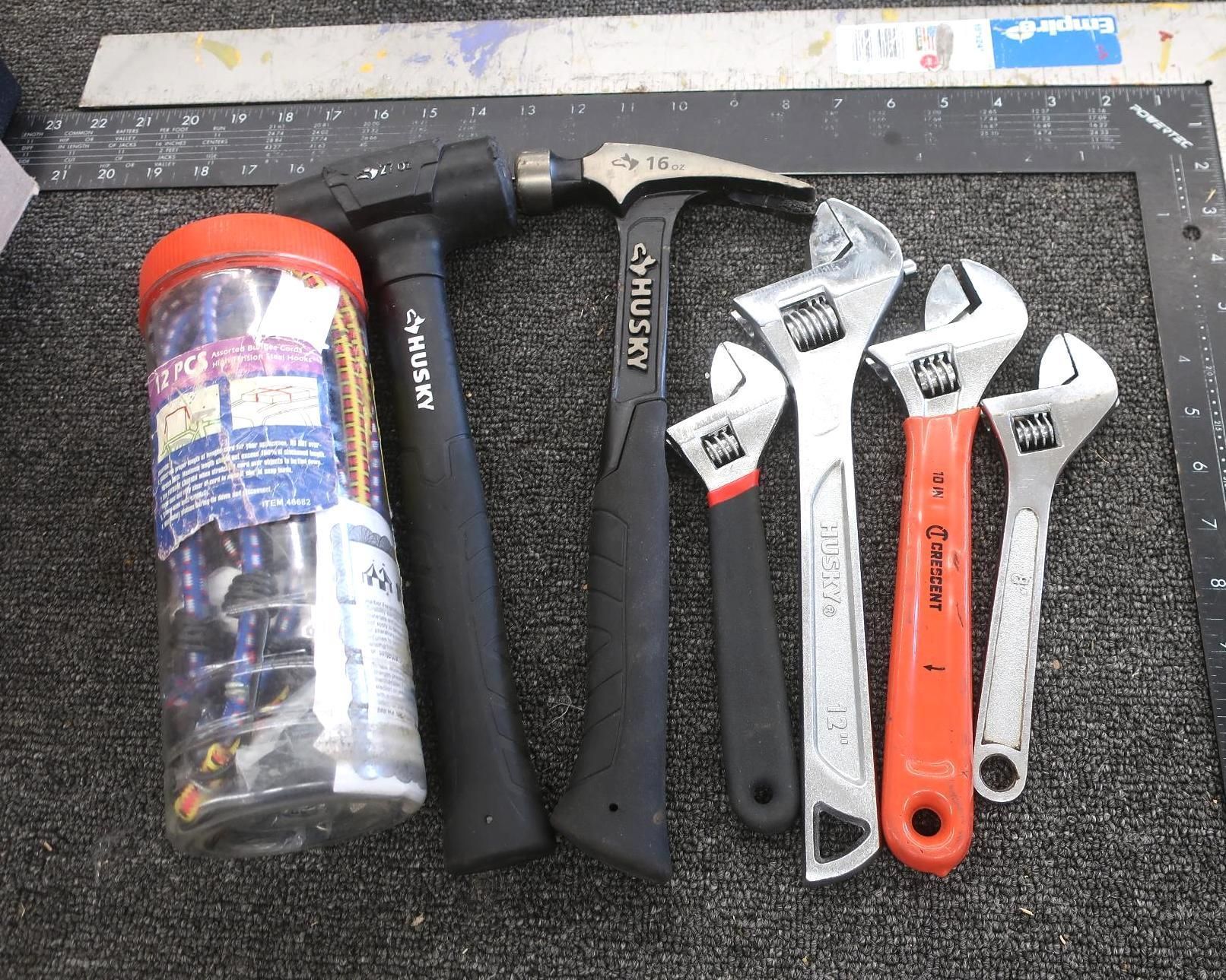 Tools: hammers, adjustable wrenches, fasteners, ruler, and square on a textured surface.