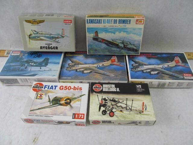 Seven vintage model airplane kits in boxes on a surface.