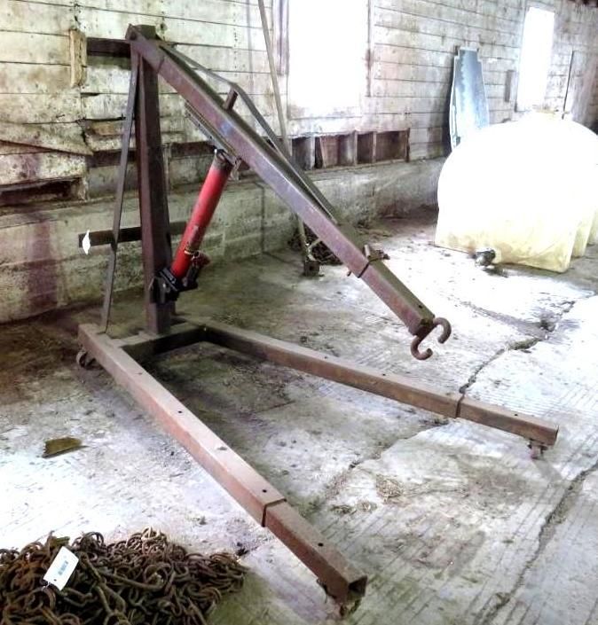 An engine hoist in a room with a concrete floor, wooden walls.