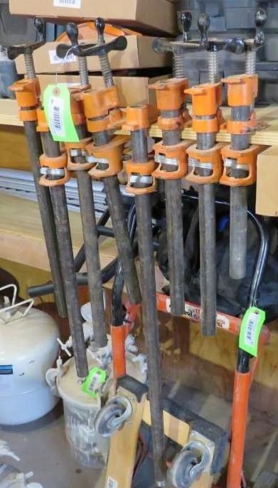 Clamps in a workshop setting, various lengths, orange and black.