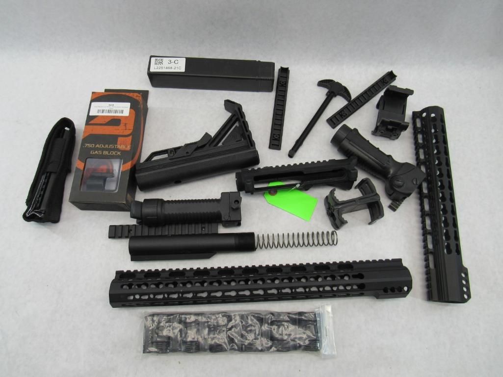 Various disassembled firearm parts laid out on a surface, including rails, barrels, and a grip.