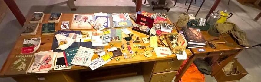 A table with books, pamphlets, and objects; items arranged on the wooden surface.