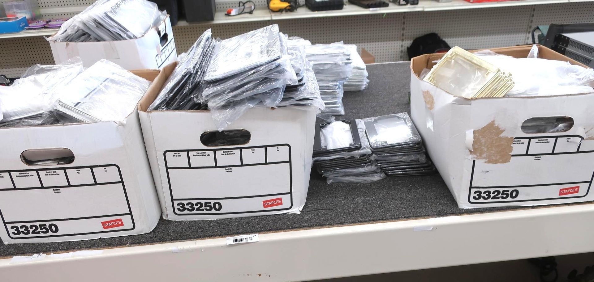 Boxes of items, possibly electronics or media, on a shelf. The boxes are labeled and stacked.