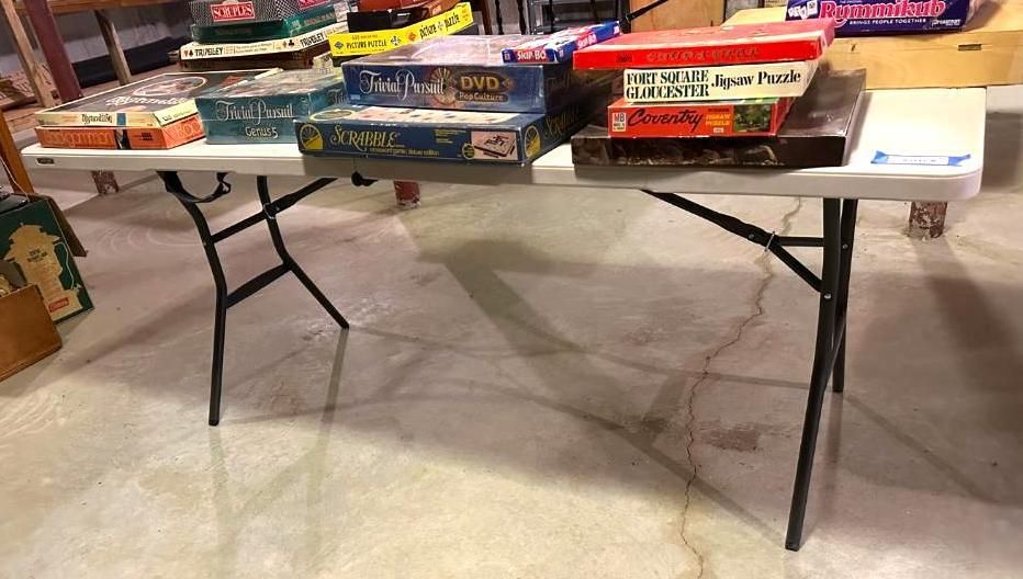 A white folding table displays several board games.