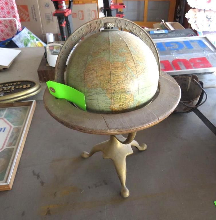 Globe in a brass stand, brown wooden ring around the globe with a yellow tag.