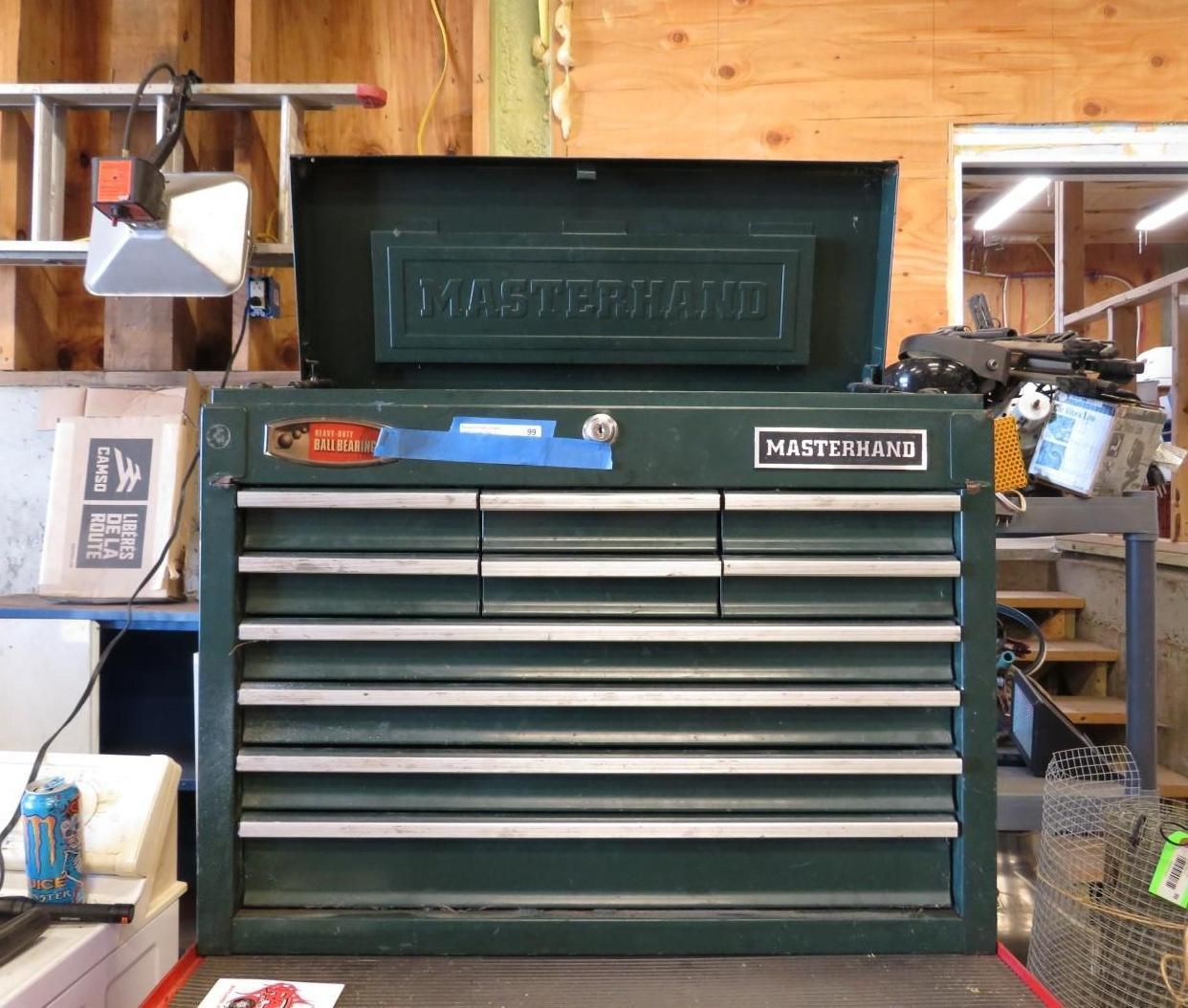 Green Master Mechanic toolbox with open top and drawers, in a workshop setting.