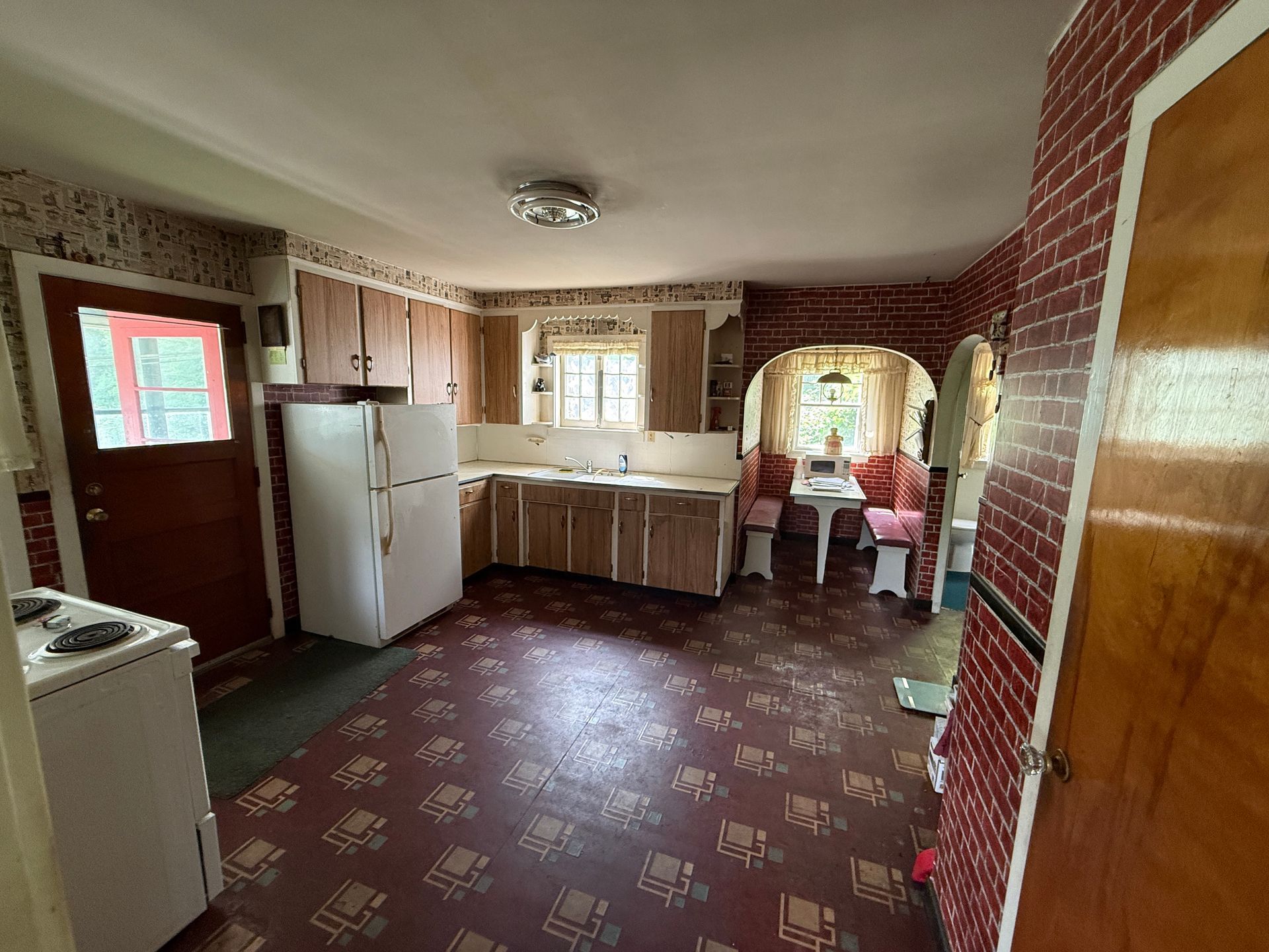 Small kitchen with red walls, white cabinets, a refrigerator, and a patterned floor.