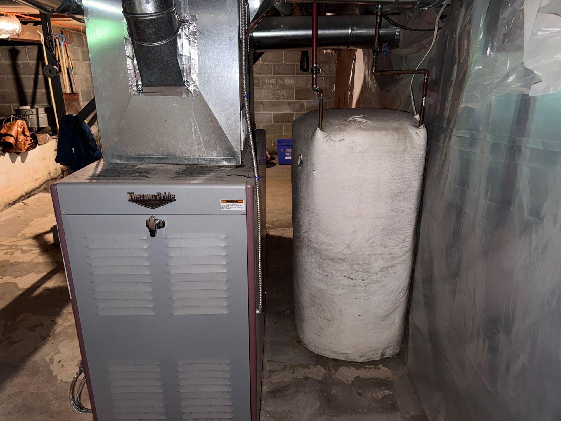 Basement HVAC room with a gray furnace cabinet, ductwork, and a white water heater.