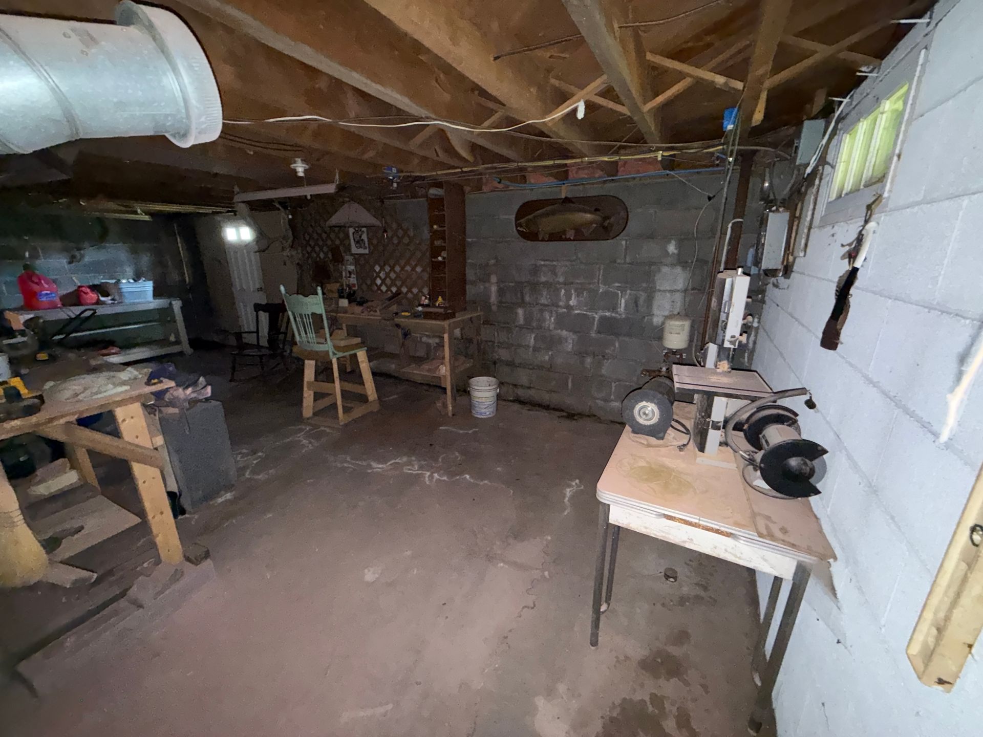 Basement workshop with exposed beams, cinderblock wall, workbench
