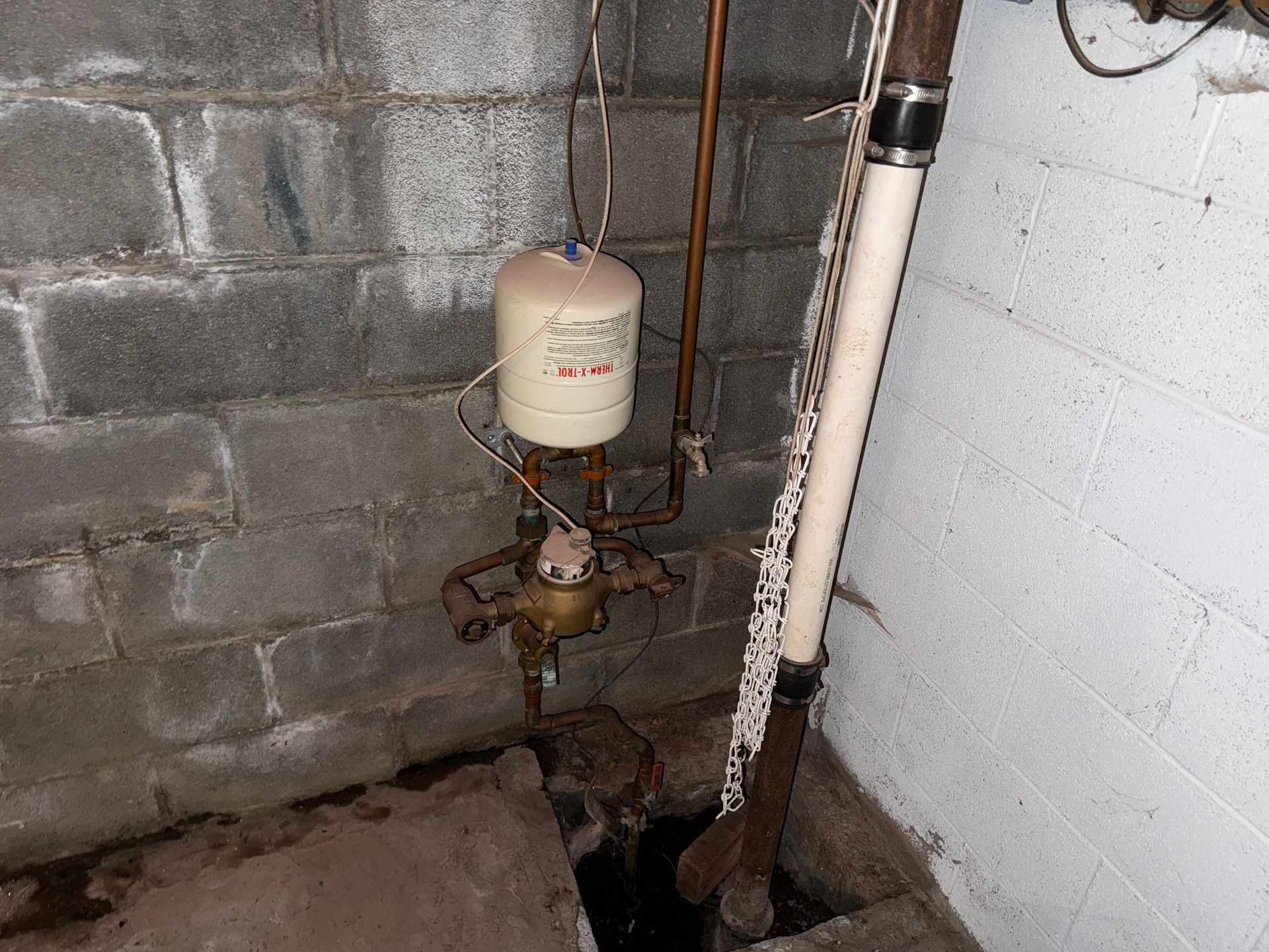 water meter and pipes against cinderblock and painted basement walls