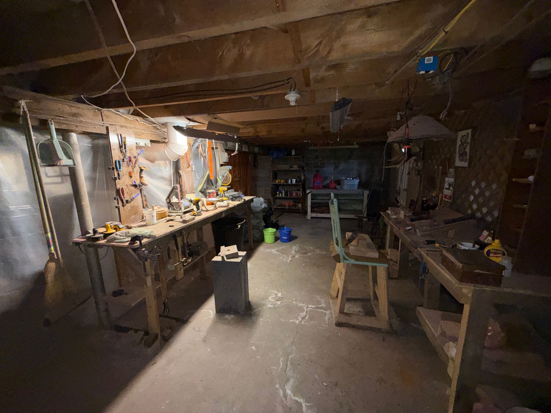 wooden workshop with benches, tools, and hanging lights in a basement-like room