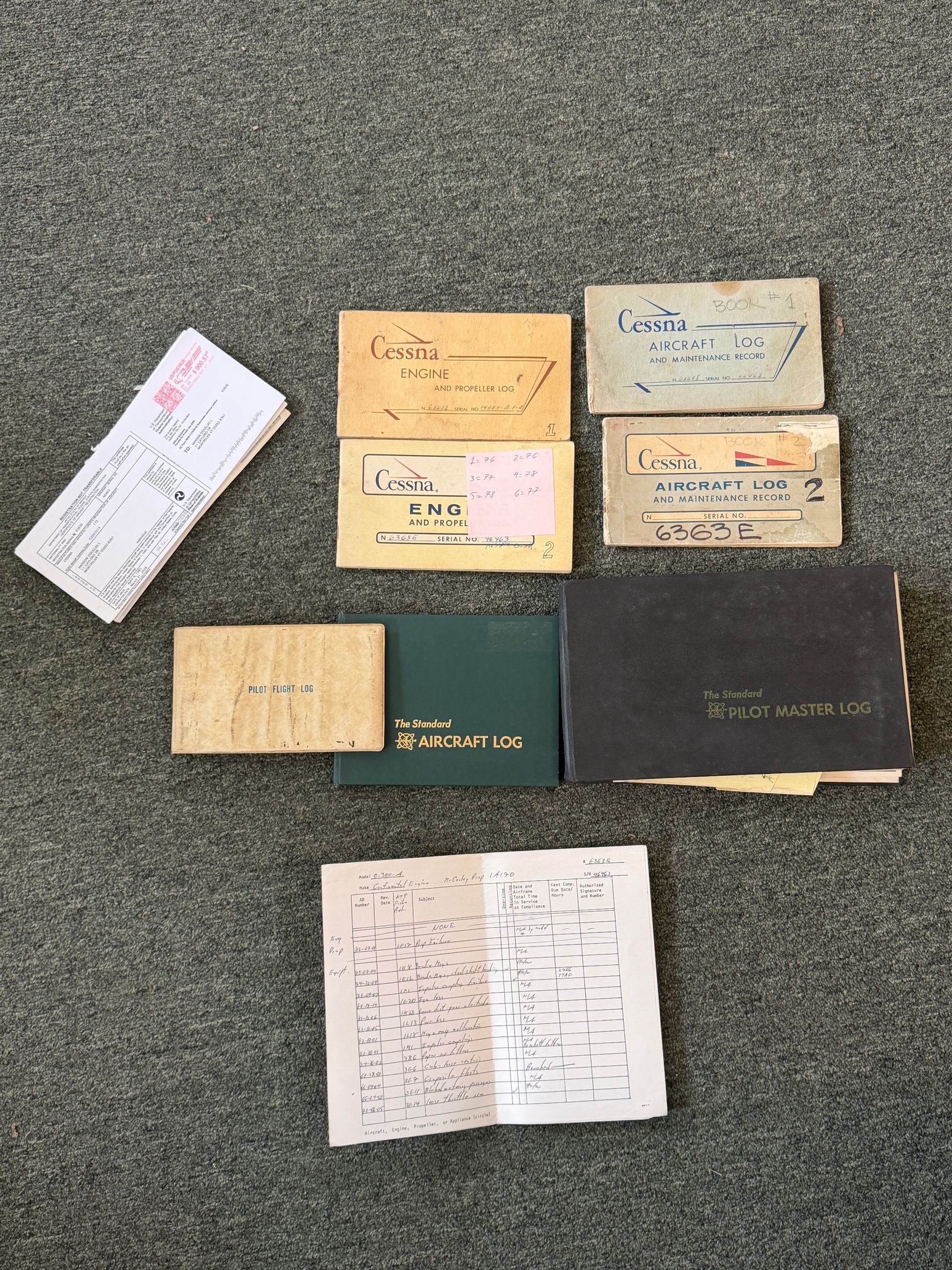 Nine vintage notebooks and papers arranged on a gray carpet.