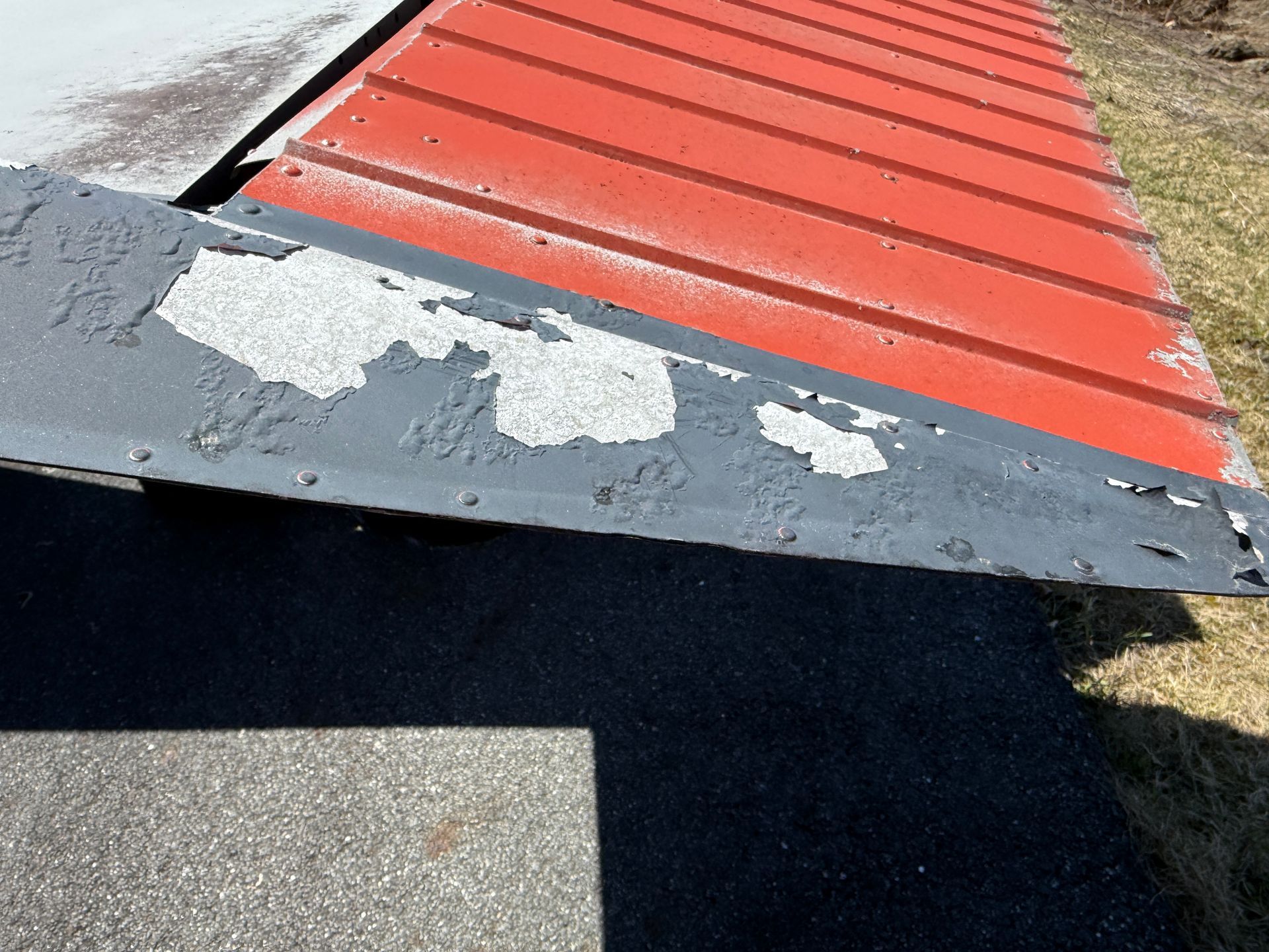 Close-up of a red-and-gray painted metal wing edge with chipped paint and worn surface.