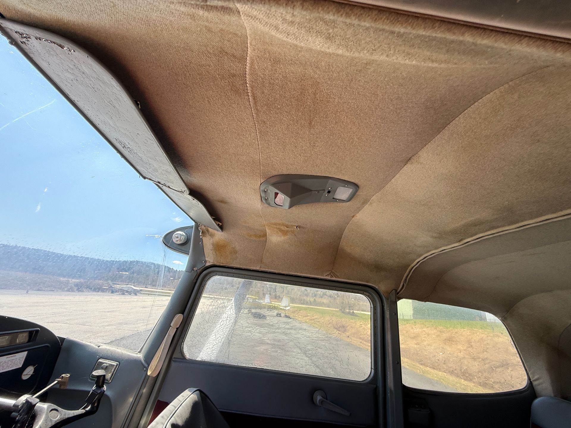Inside a small airplane cockpit with beige ceiling and windows