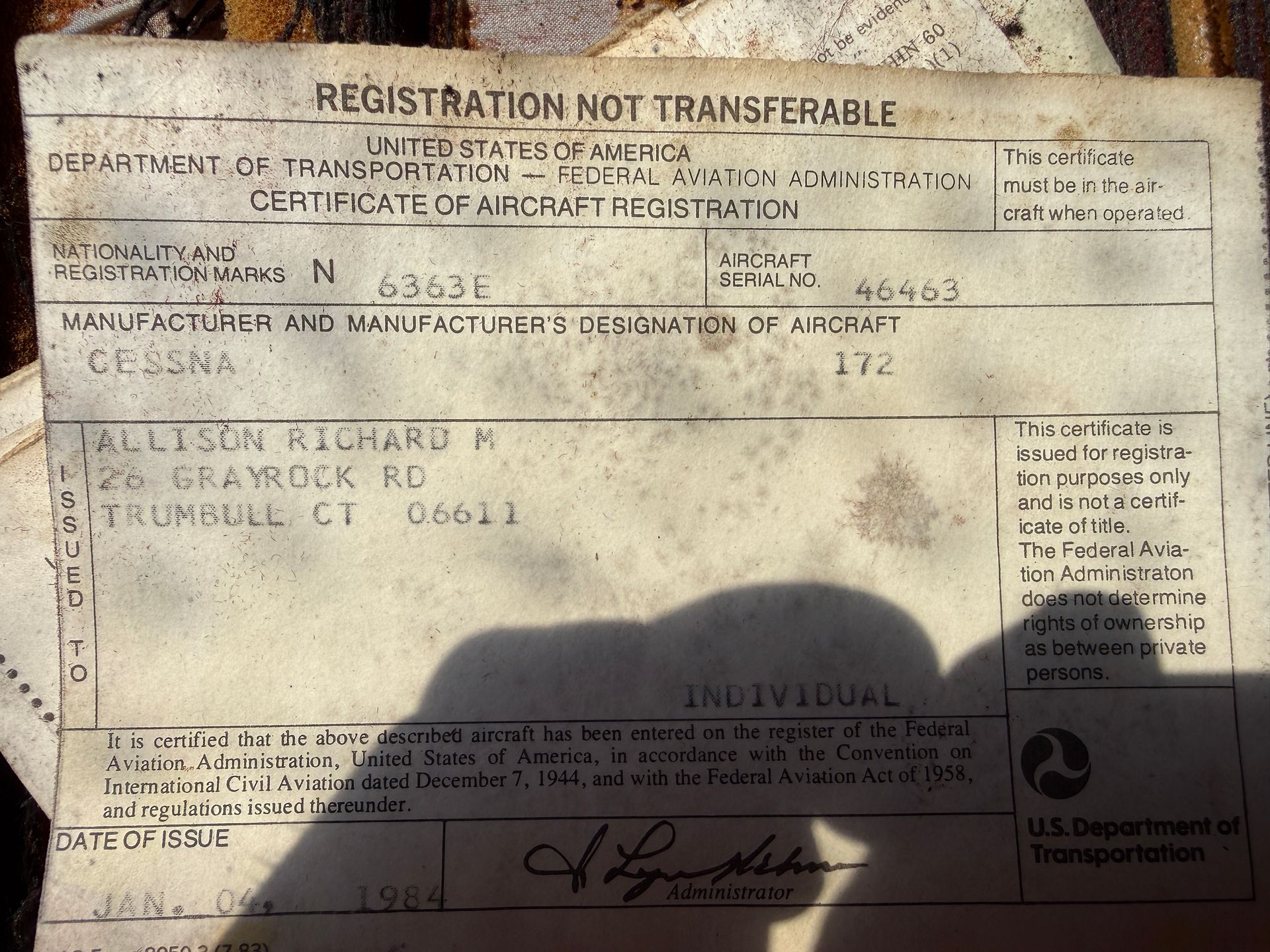 Close-up of a worn vehicle registration certificate with faded text and a shadow across the bottom.