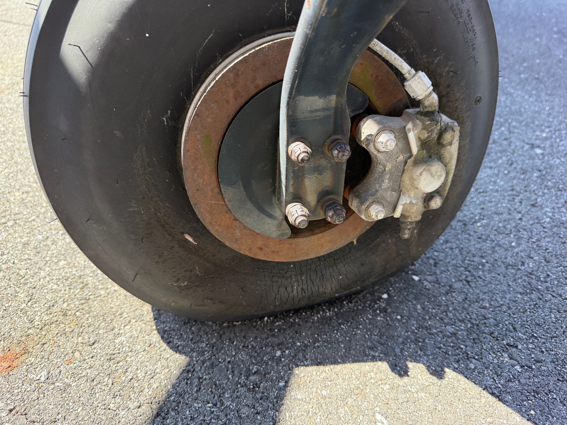 Close-up of a small aircraft wheel and landing gear on pavement, showing the brake assembly.
