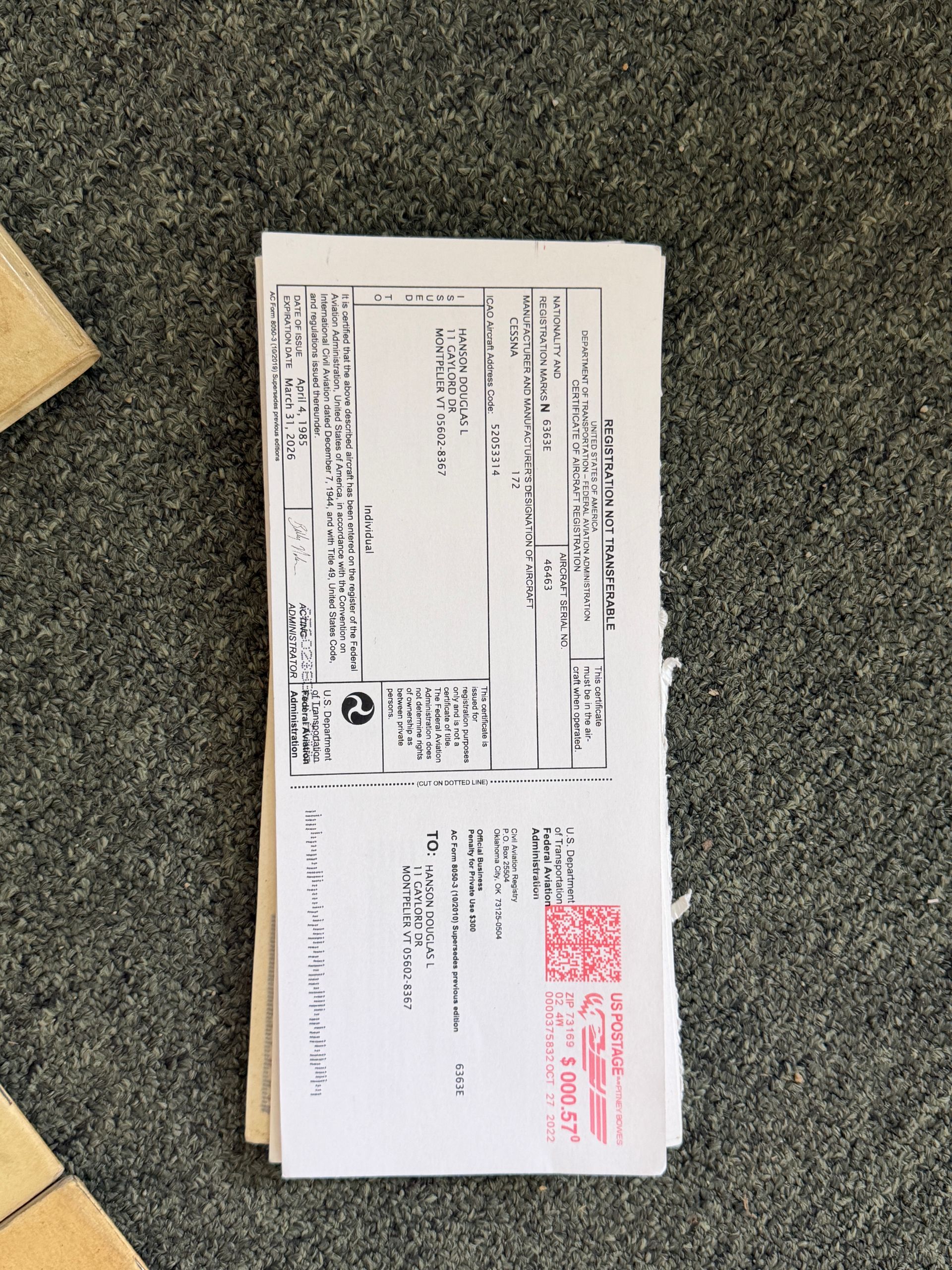 White envelope with Japanese text and red stamps lying on a textured gray carpet