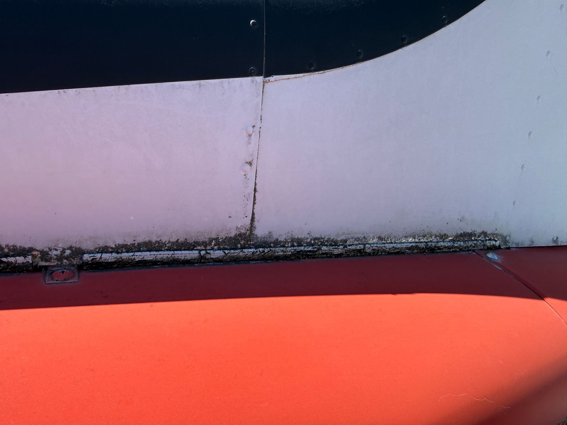 Close-up of a red and white curved aircraft tail with a vertical seam and dark trim at the top