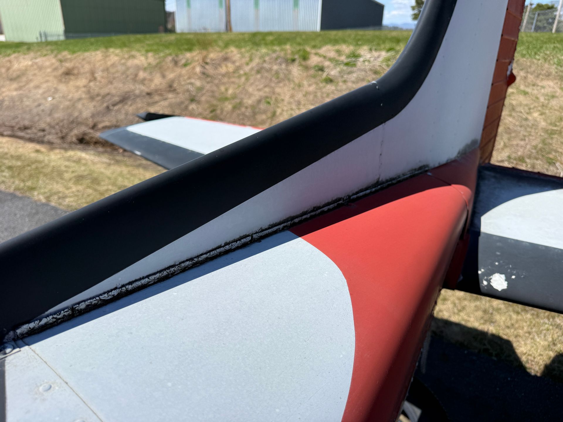 Close-up of a red, black, and white aircraft tail section outdoors
