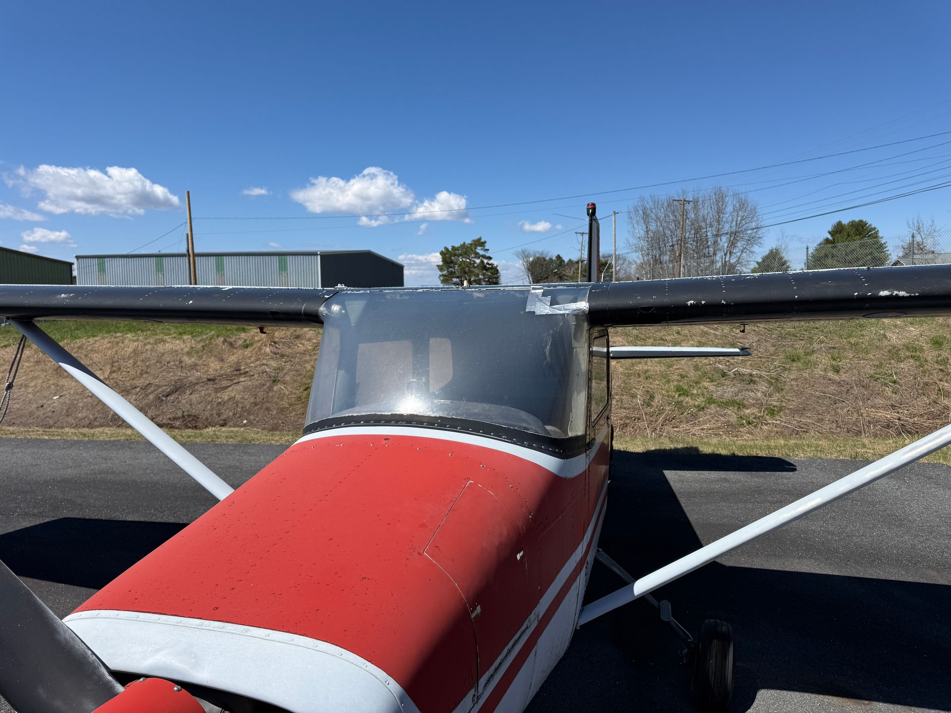 Small red-and-white airplane parked on a runway under a clear blue sky