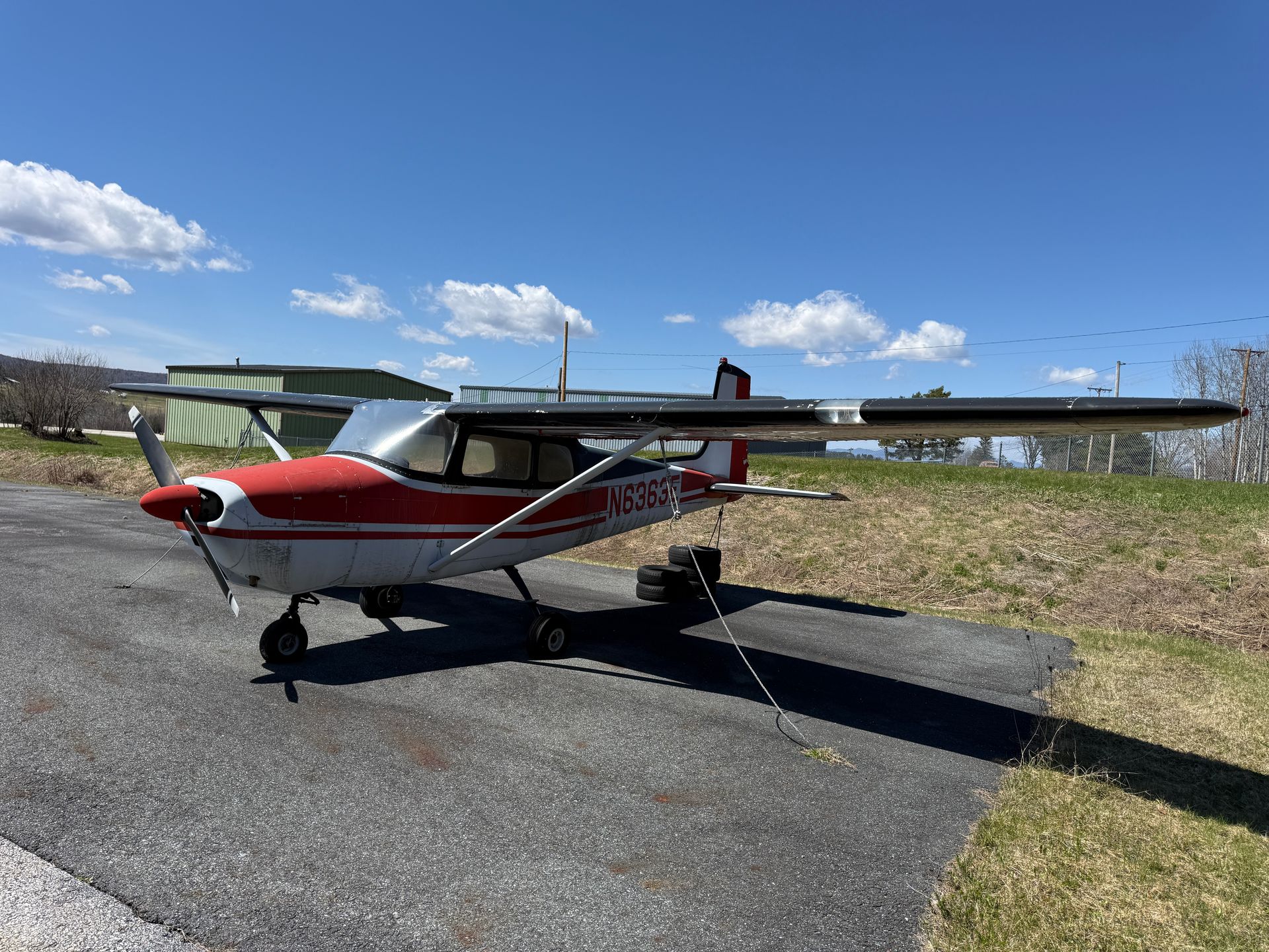 Small red-and-white single-engine airplane parked on a runway under a blue sky