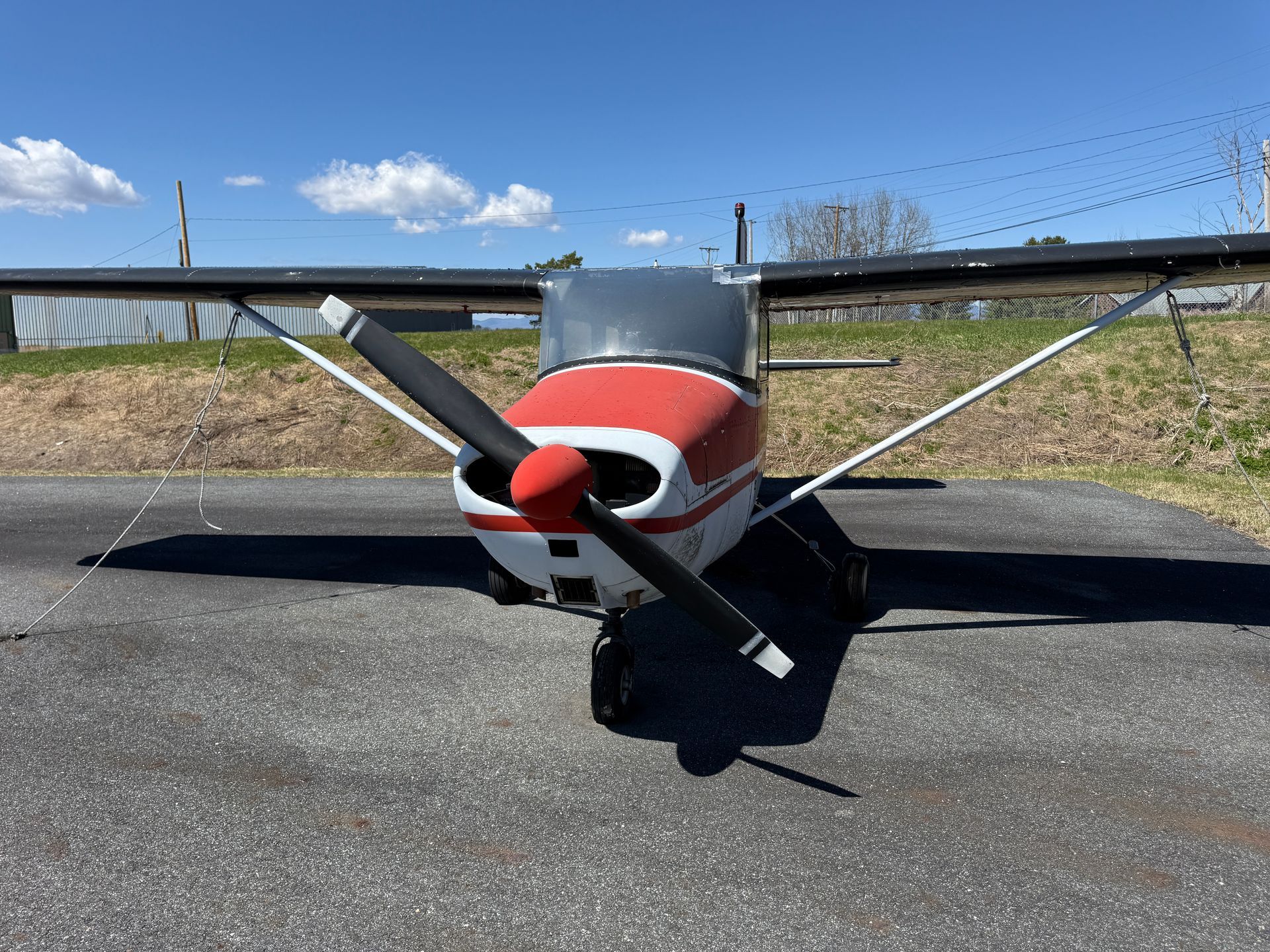 Small red-and-white airplane parked on a runway under a blue sky