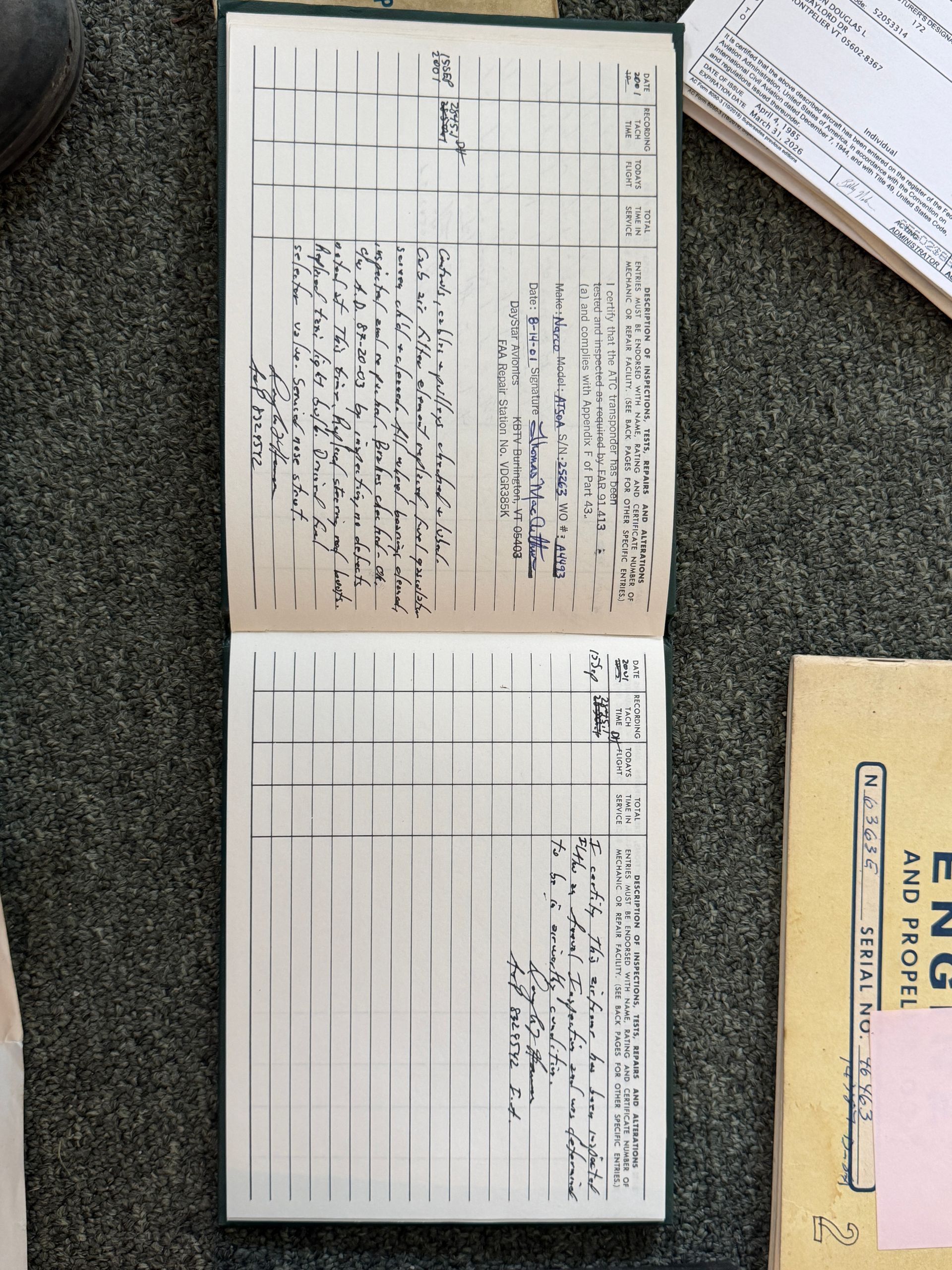 Open ledger with handwritten notes on a gray surface, next to a yellow envelope and pink slip.