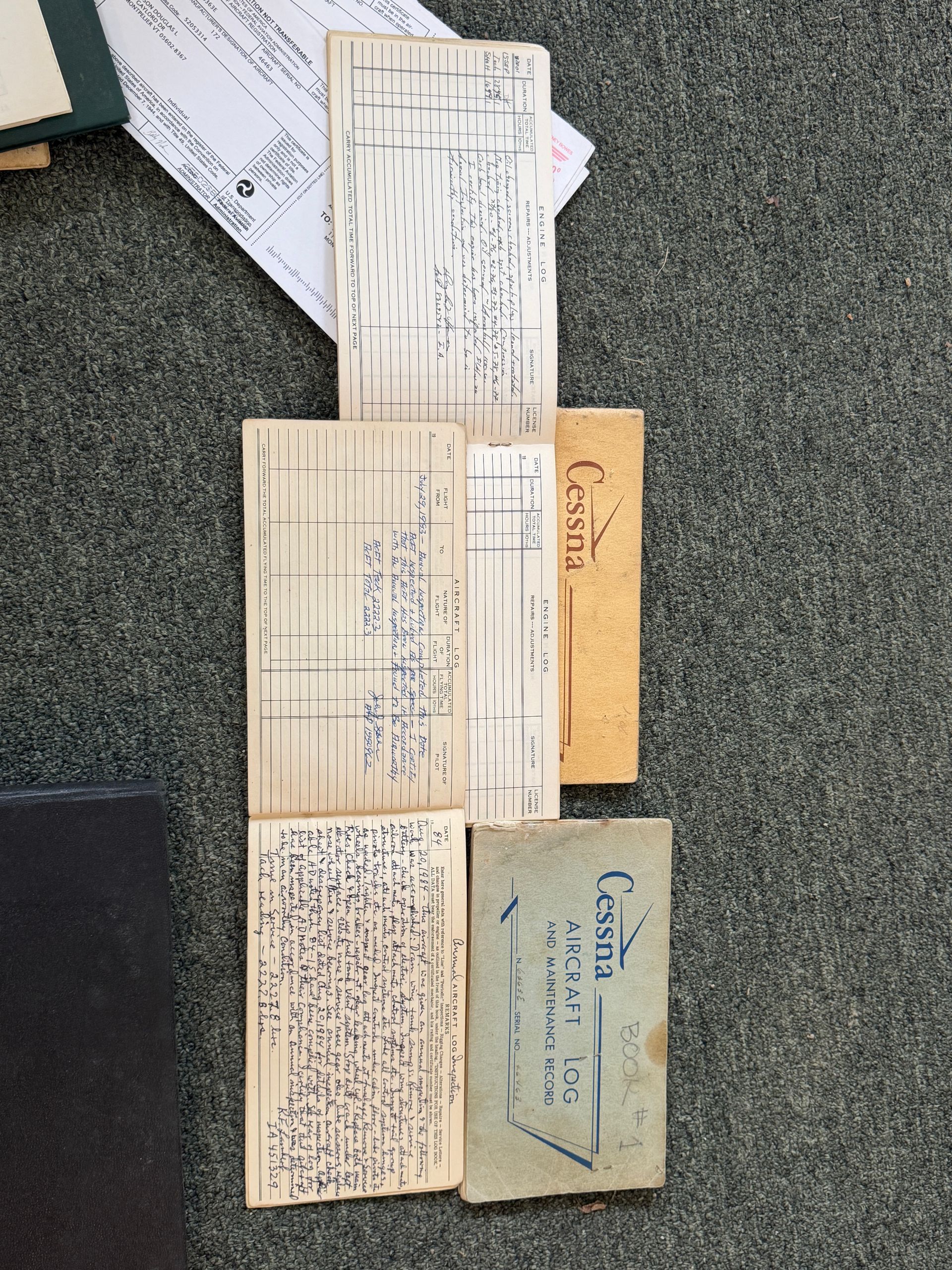 Vintage paper forms and envelopes on a gray carpet, with handwritten notes visible.
