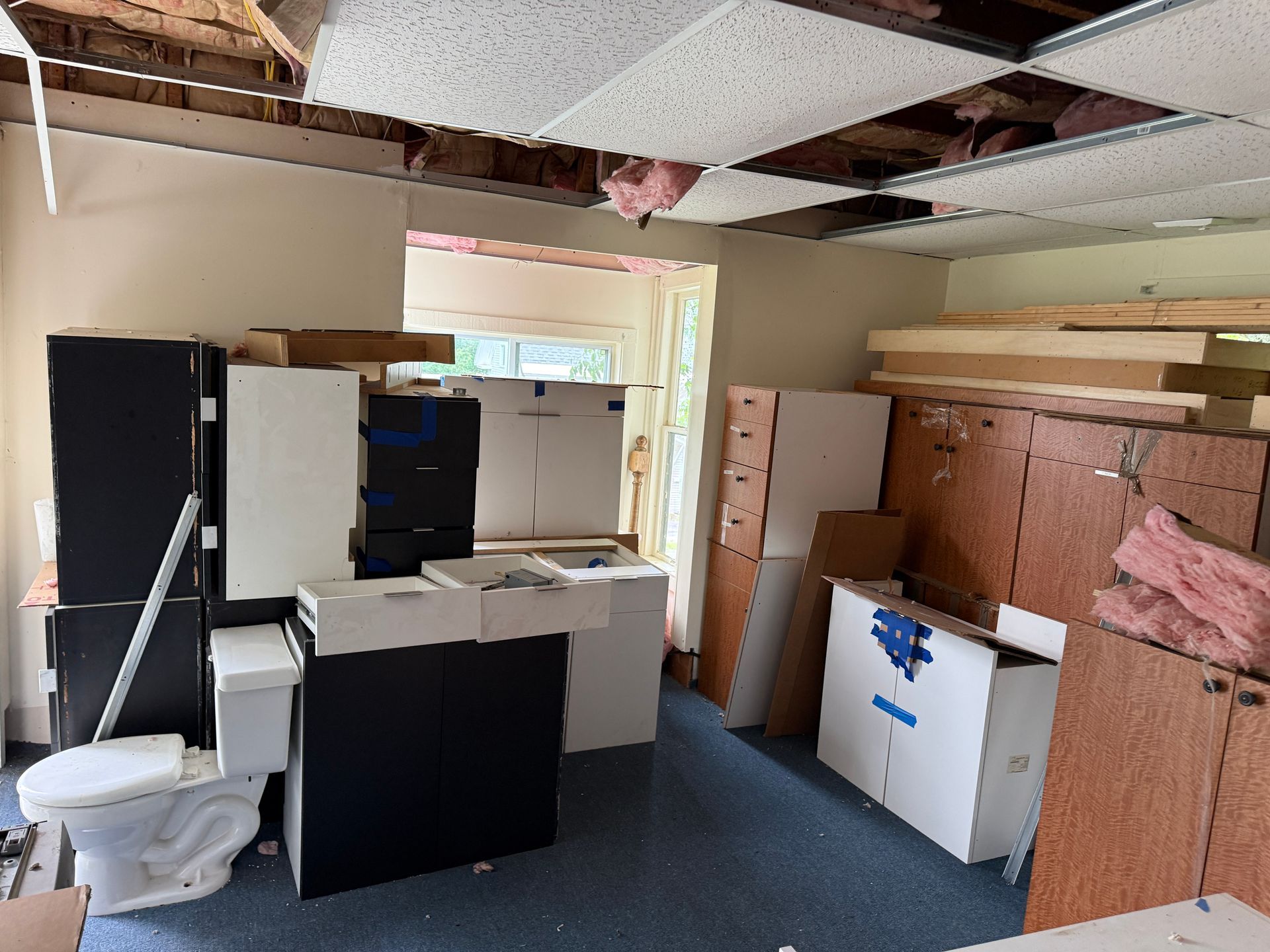 room with ceiling tiles, cabinets, and boxes on the floor