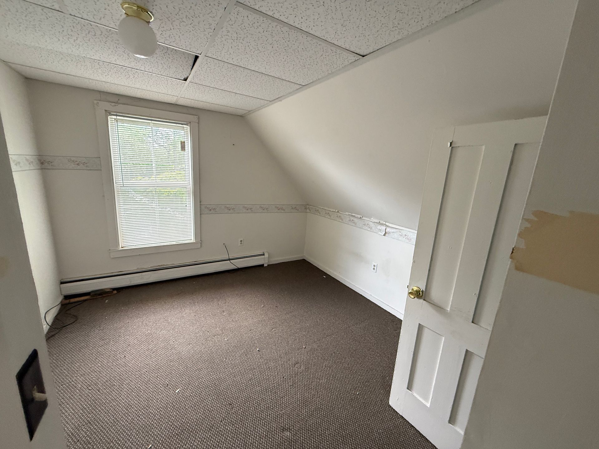 Empty carpeted room with white walls, window blinds, and an open closet door.