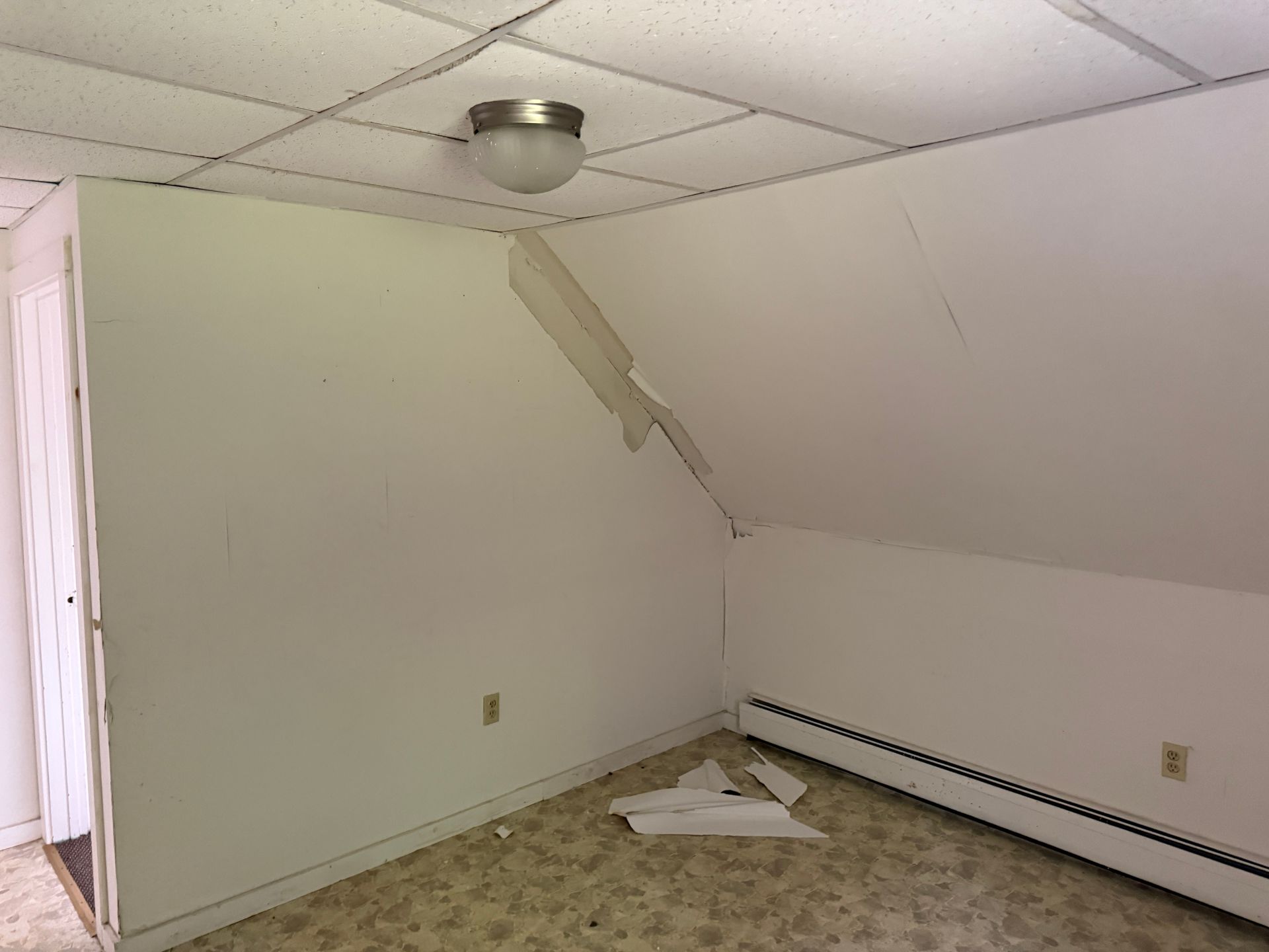 Empty attic room with sloped ceiling, white walls, carpet, and a ceiling light fixture