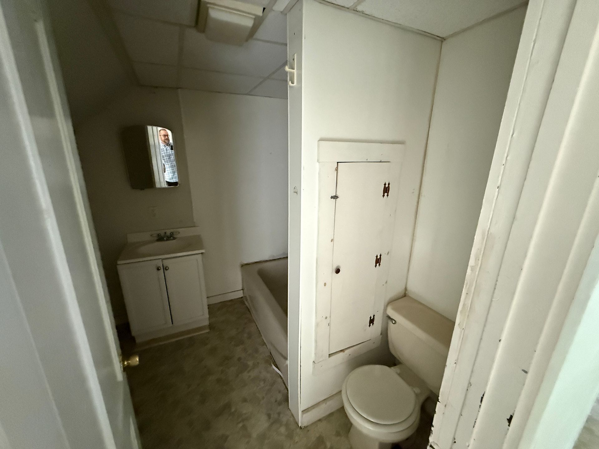 Small bathroom with toilet, sink, and shower stall in white and beige tones.