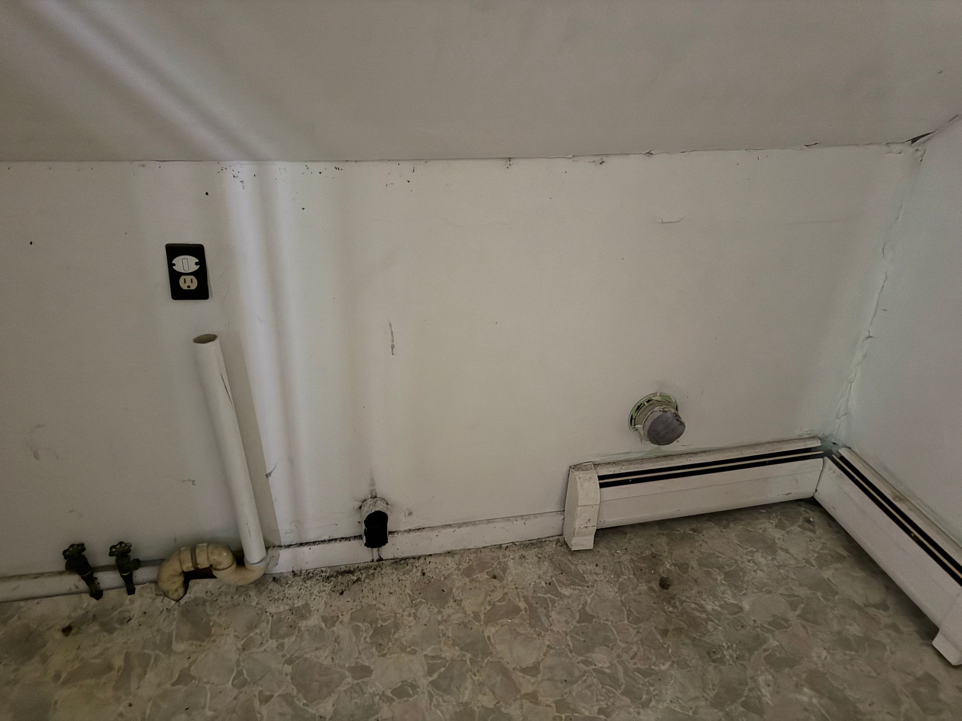 Small unfinished room corner with white walls, and a tiled floor