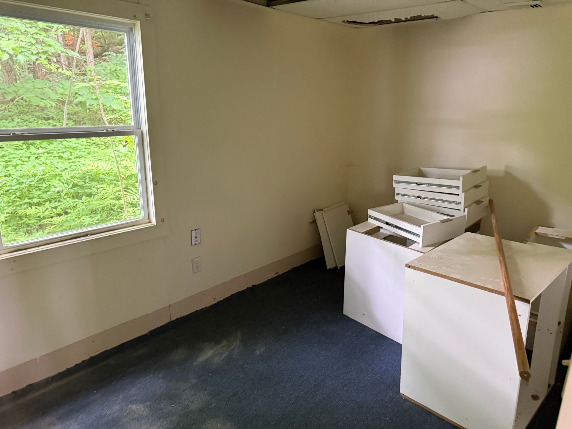 Empty room with a window, beige walls, dark carpet