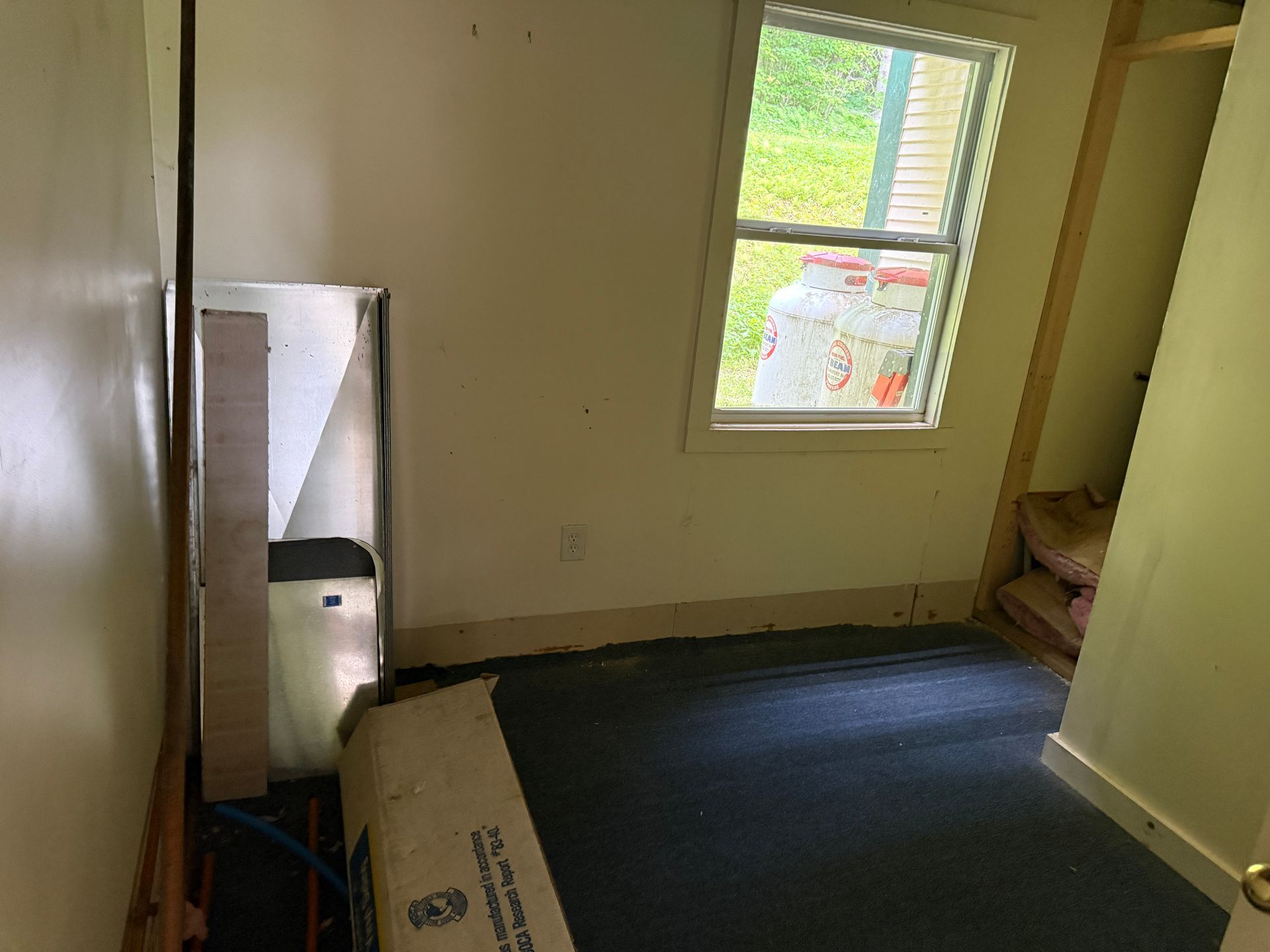 Empty bedroom with beige walls, window, and dark carpet
