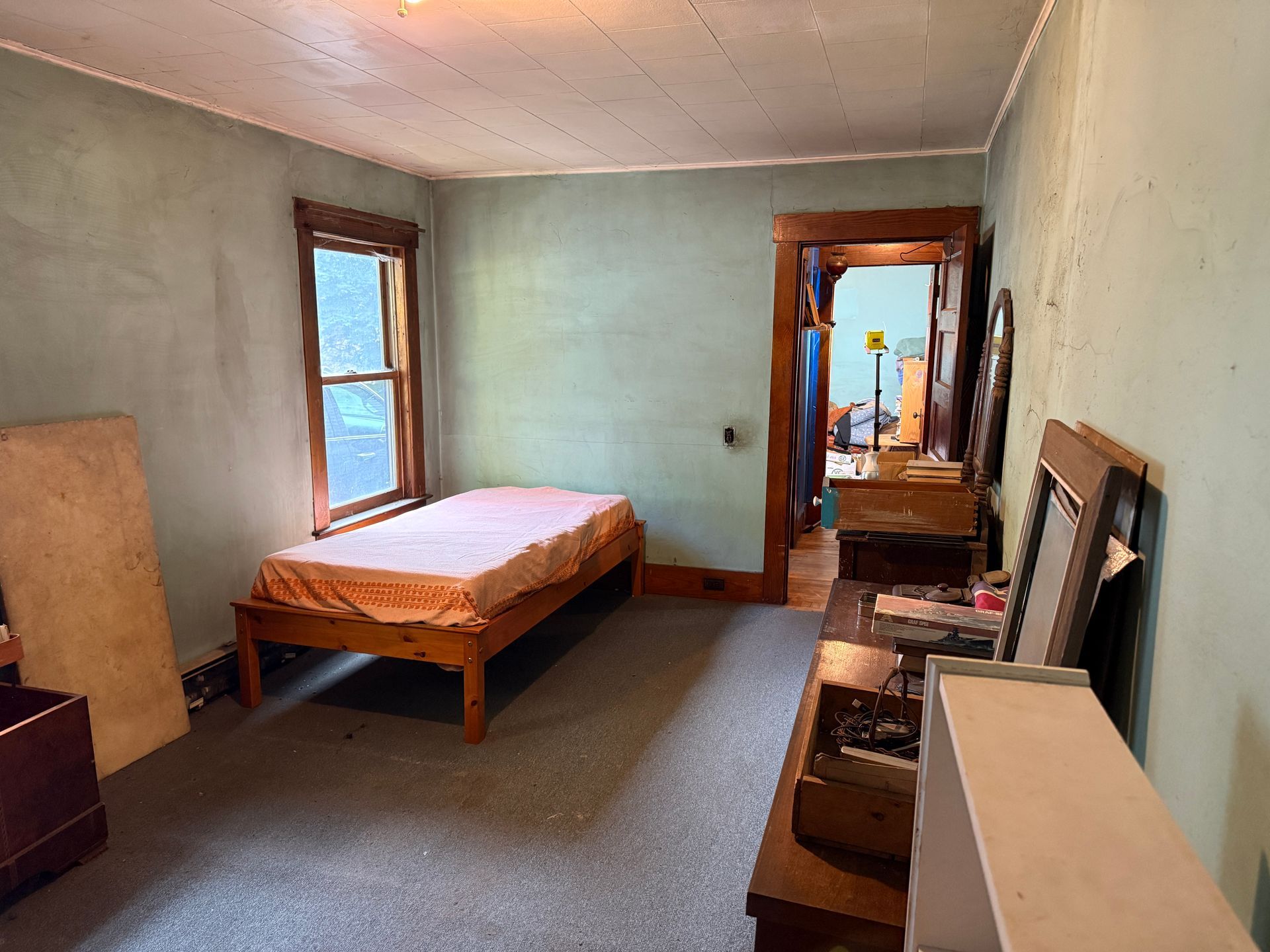 bedroom with a single bed, window, dresser, and chair in a pale green room.