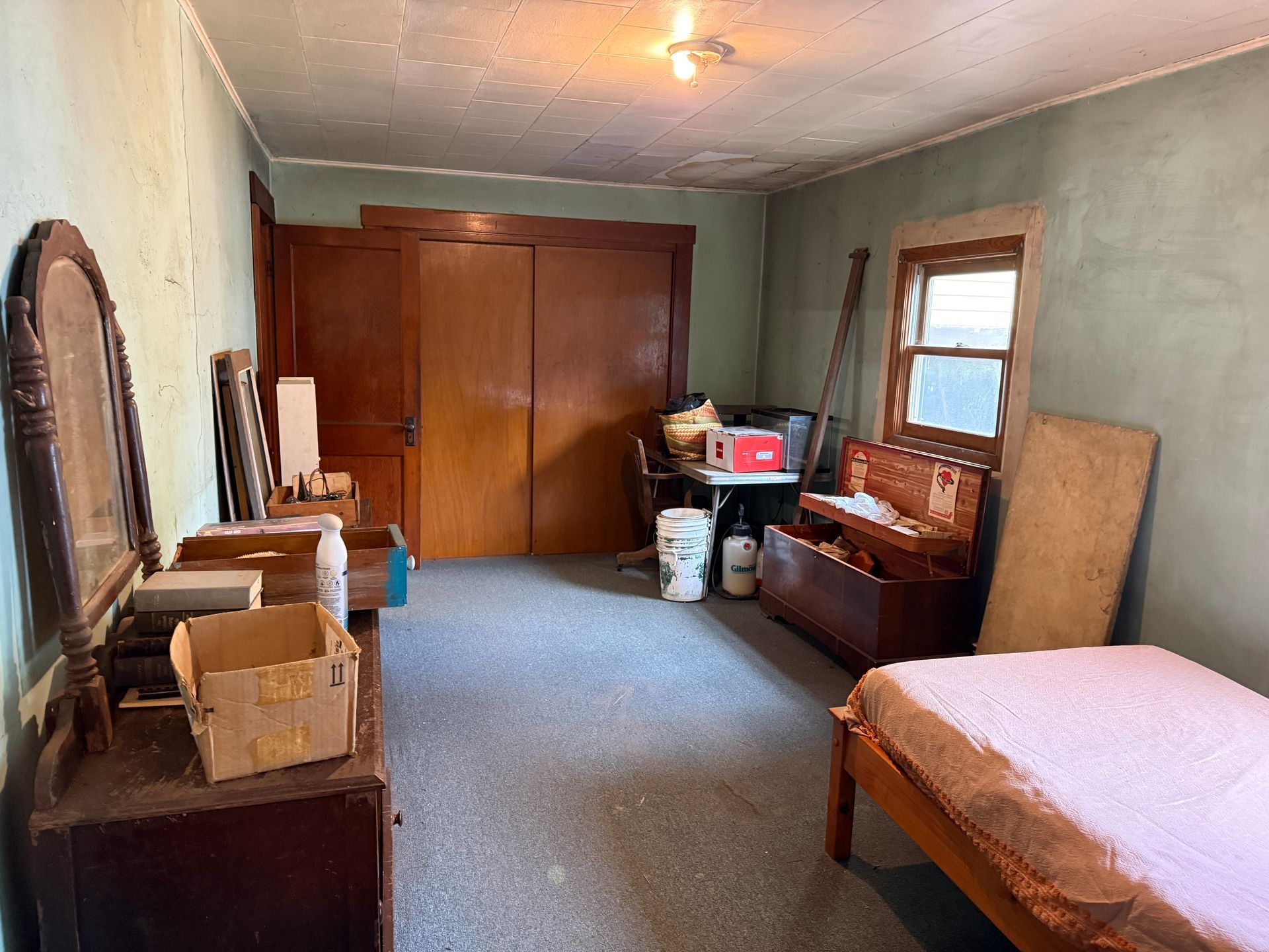 Small bedroom with wood furniture, a bed, dresser, mirror, closet, and window.