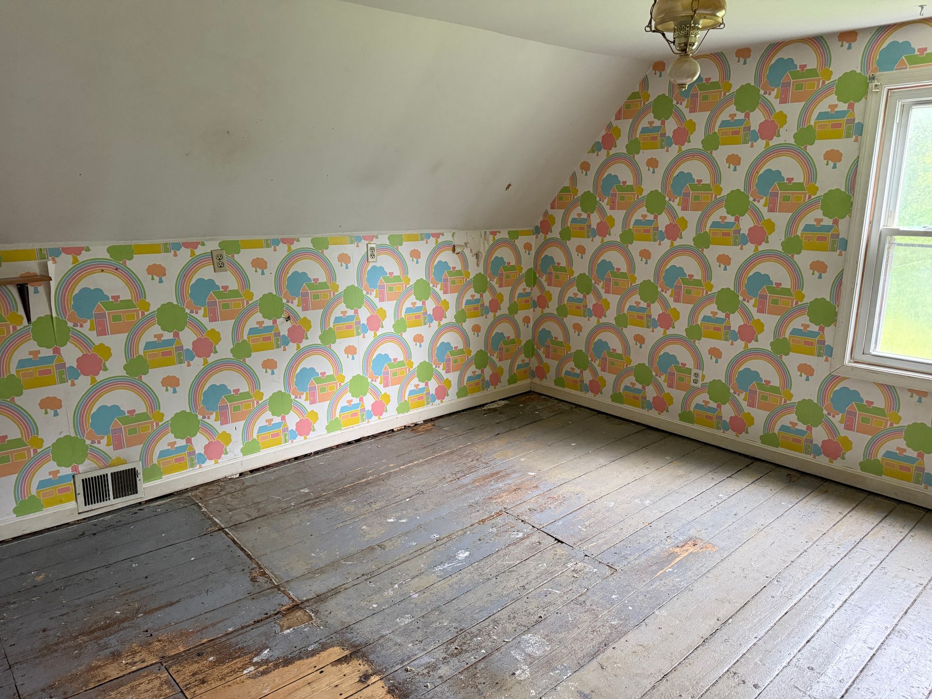 Empty attic room with colorful floral wallpaper and wooden floorboards