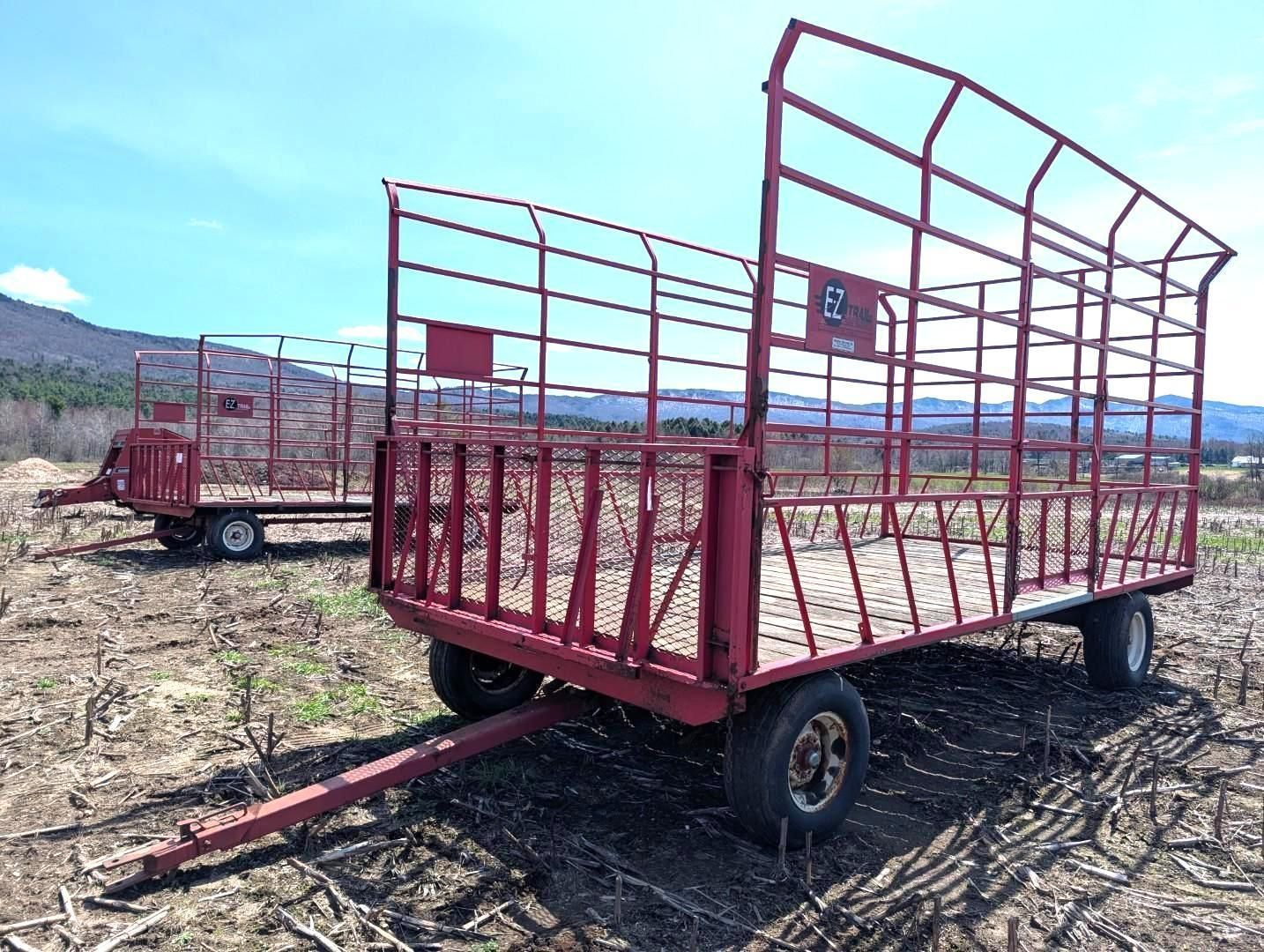 Red livestock trailer with metal cage sides parked in an open field