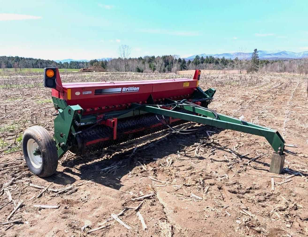 Red grain drill parked in a field under a clear sky