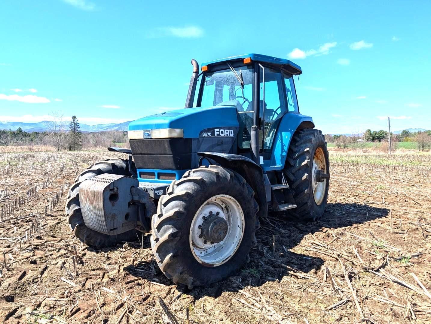 Blue tractor in a field under a bright sky